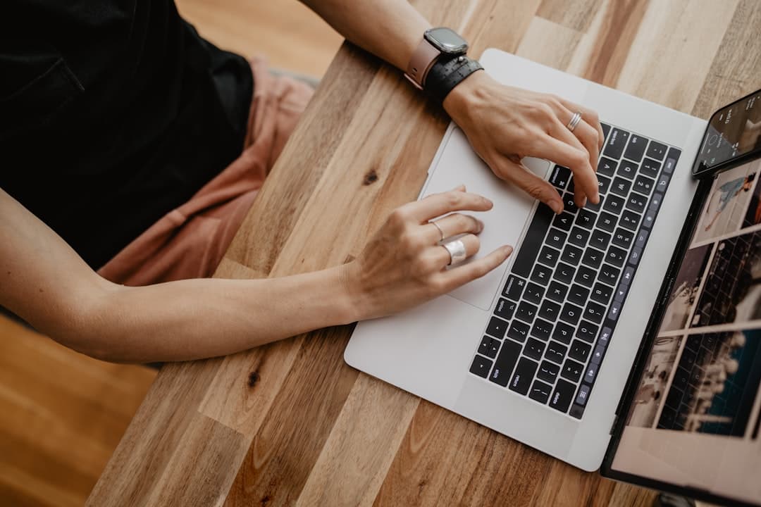 Eine Person schreibt am Schreibtisch am Fenster ein Bewerbungsschreiben und recherchiert am Laptop