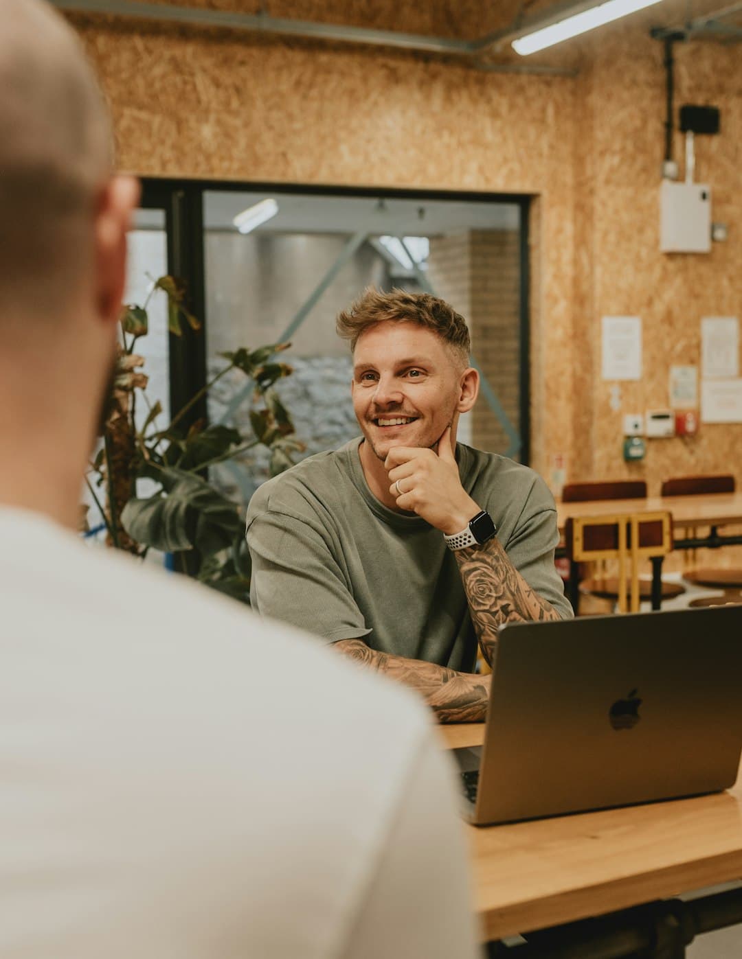 A man smiles while talking to someone.