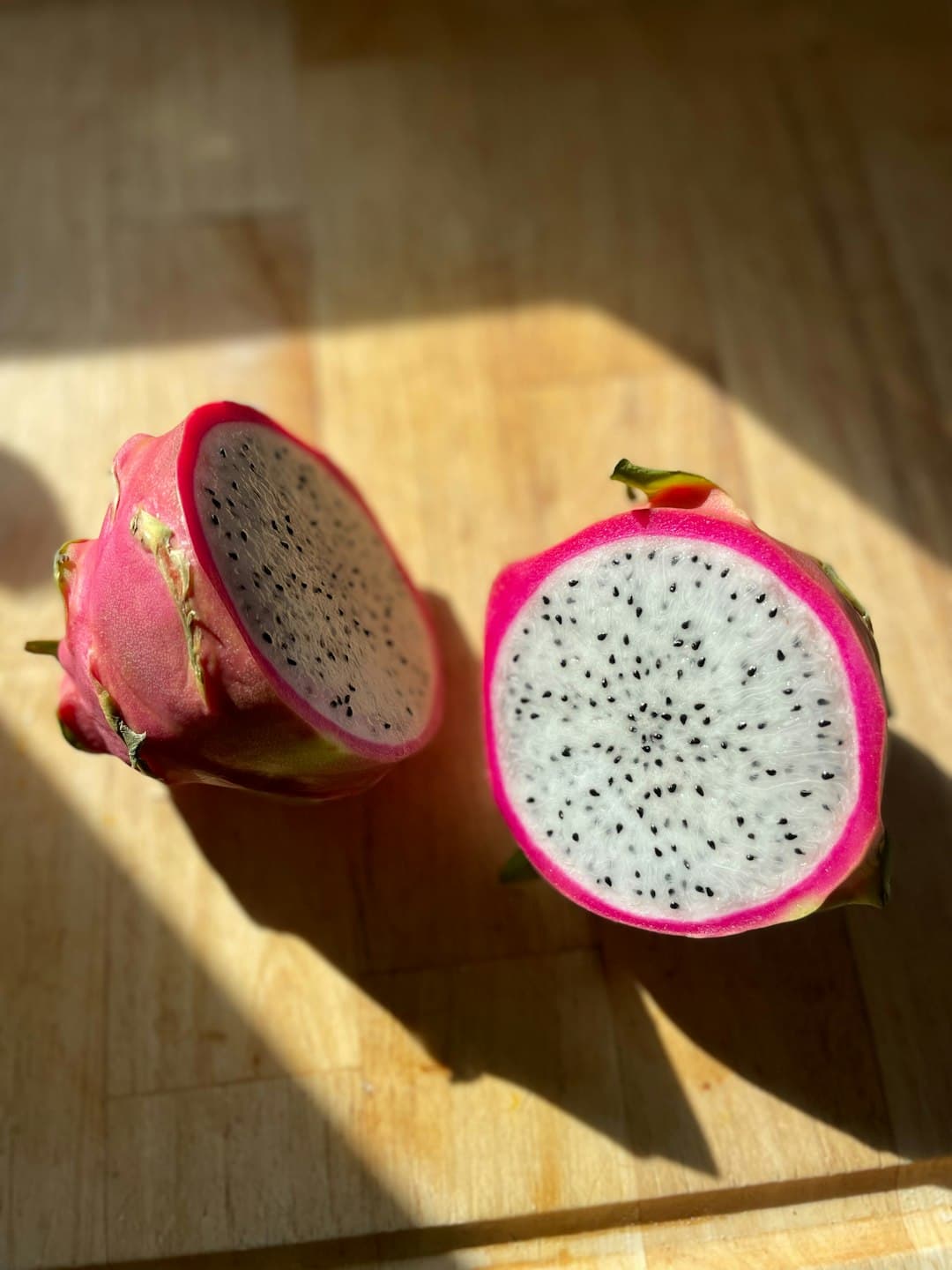 Two halves of a dragon fruit on a wooden surface