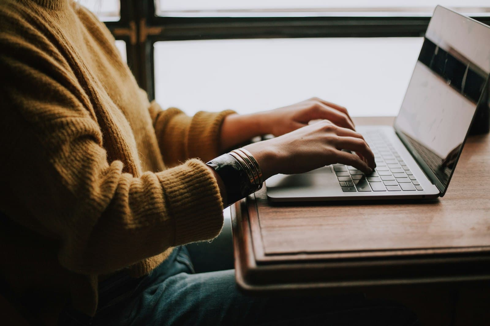 Person am Laptop bei warmem Fensterlicht