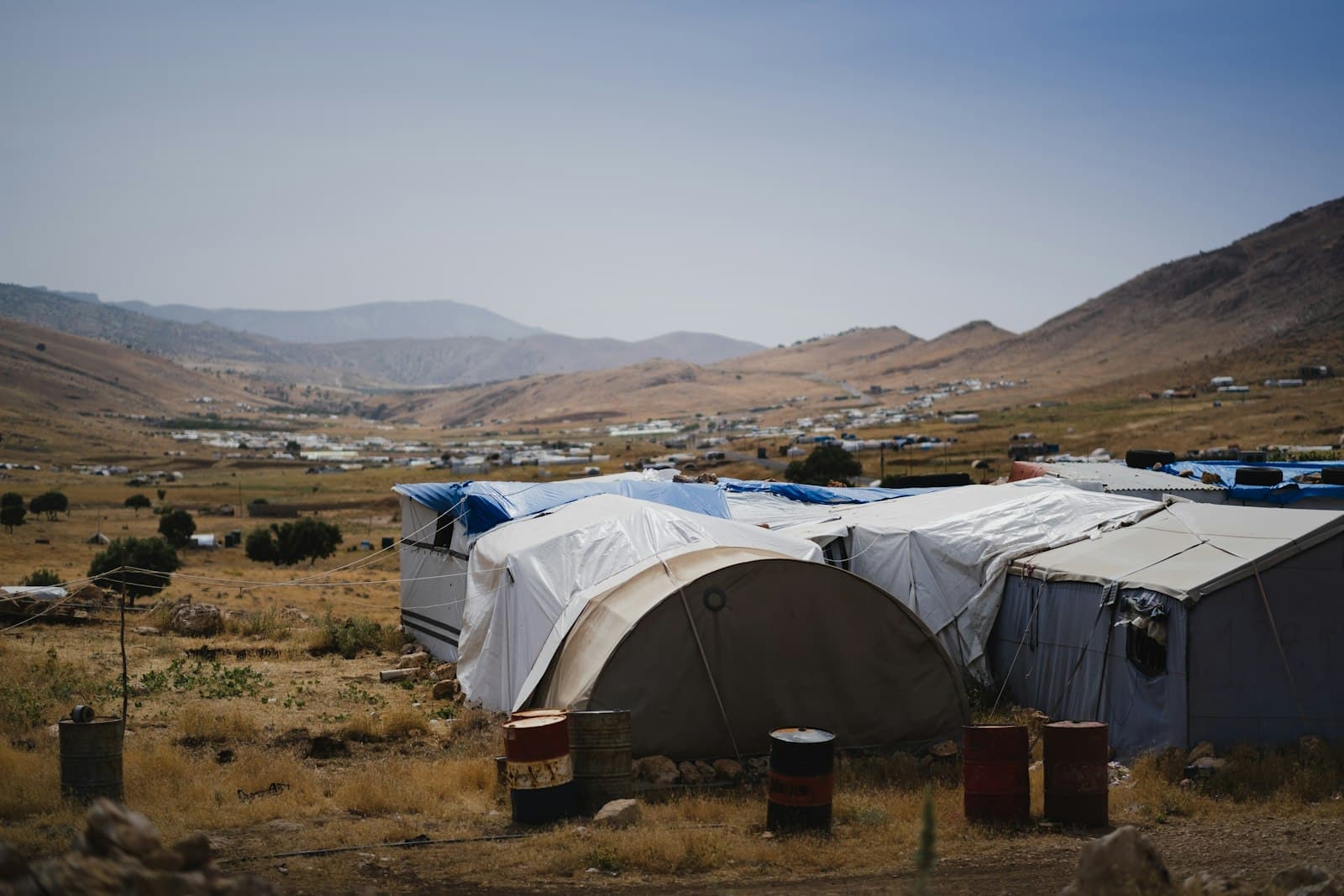 Zelte eines Lagers für Binnenvertriebene bei Sinjar im Nordirak vor trockener Hügellandschaft